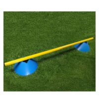 Yellow balance beam resting on blue conical supports on grass, like a playground seesaw.