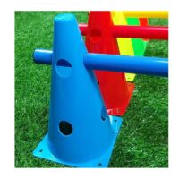 Blue conical climbing toy with holes and a horizontal blue bar, set on green grass with red and yellow parts in the background.