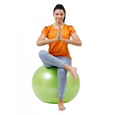 Fitlopta Gymnic Plus 55 cm 2 - AEROBIC.sk Woman in an orange shirt sits on a green exercise ball with legs crossed, hands in prayer pose.