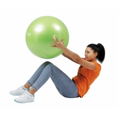 Fitlopta Gymnic Plus 55 cm 5 - AEROBIC.sk Woman in an orange shirt sits with knees bent, holding a large green stability ball in front of her for a core exercise.