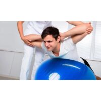 Fitlopta PhysioBall Standard 85 cm 2 - AEROBIC.sk Man stretching over a blue exercise ball while a trainer holds his arm to guide the stretch.